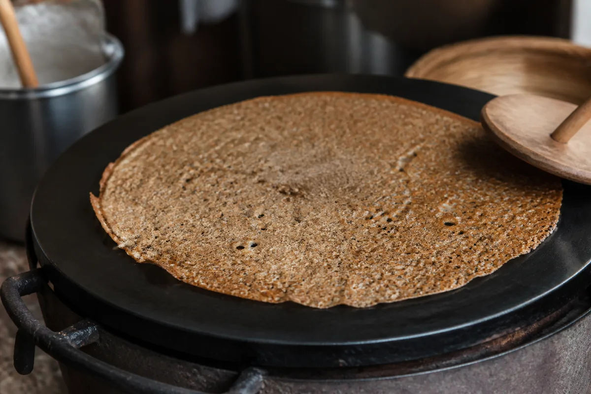 Galette de blé noir en cuisson sur une billig traditionnelle bretonne