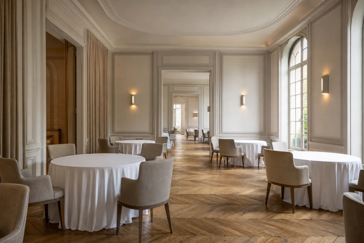 Salle de restaurant gastronomique dressée avant le service, nappes blanches et lumière naturelle